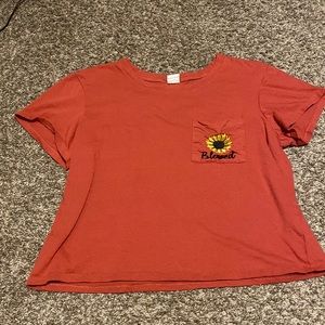 Burgundy-pink crop top shirt. With a pocket containing a sunflower.
